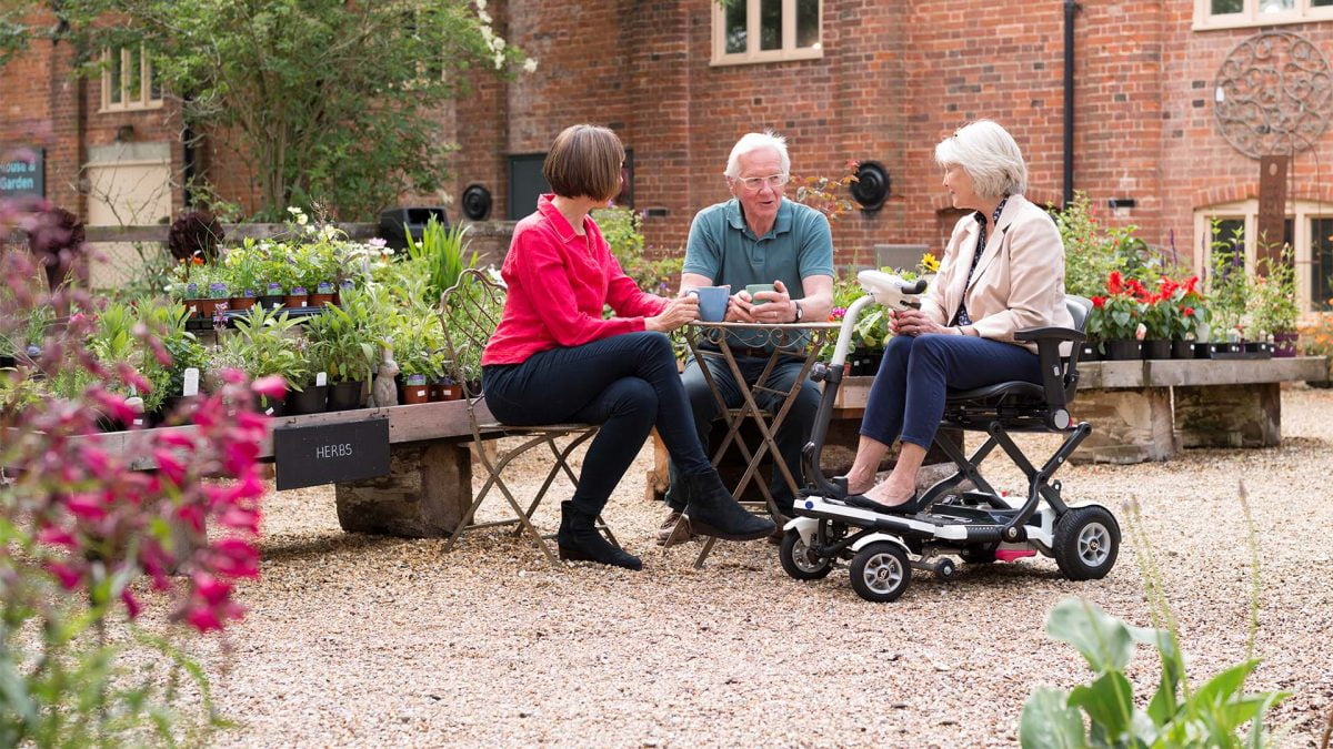 3 people sitting together with 2 of the people on mobility scooters