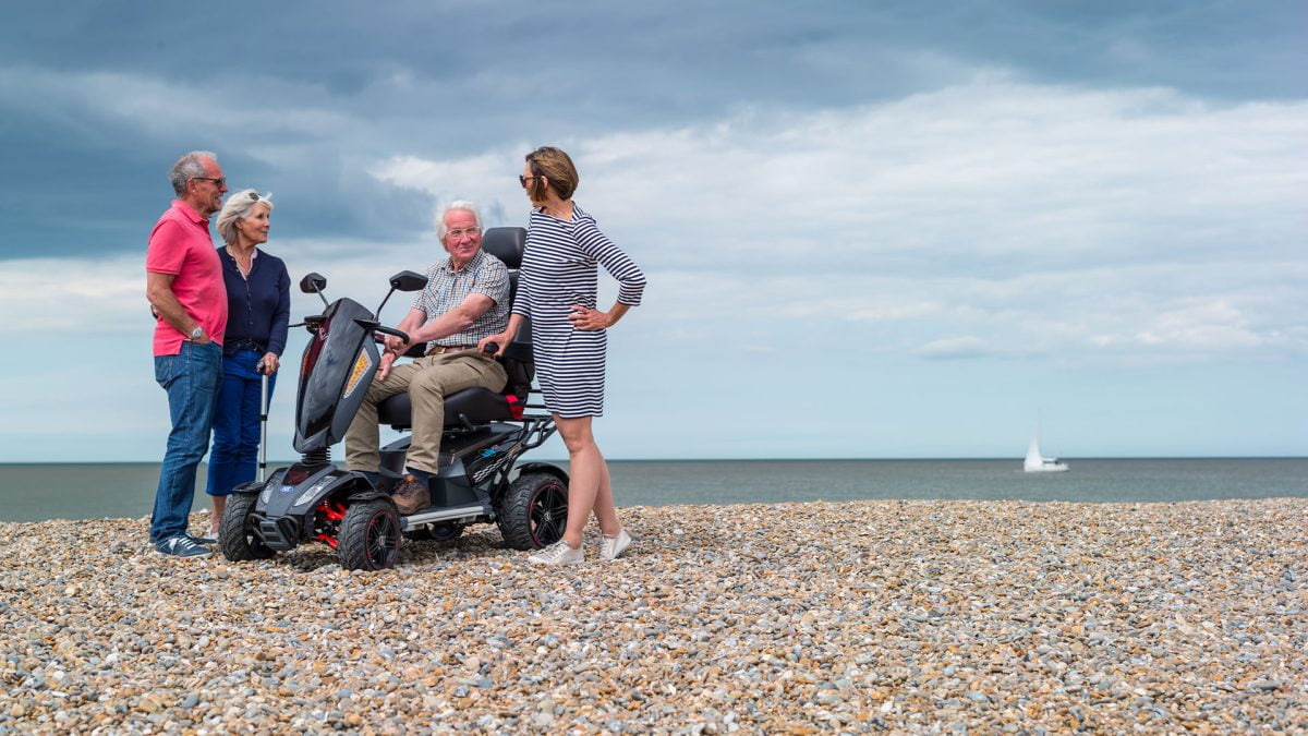 A family on the beach with one on an all terrain mobility scooter